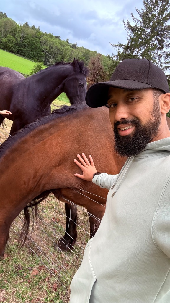 Tommo smiling and fit next to a brown horse